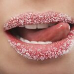 Applying sugar lip scrub to dry, chapped lips for exfoliation.