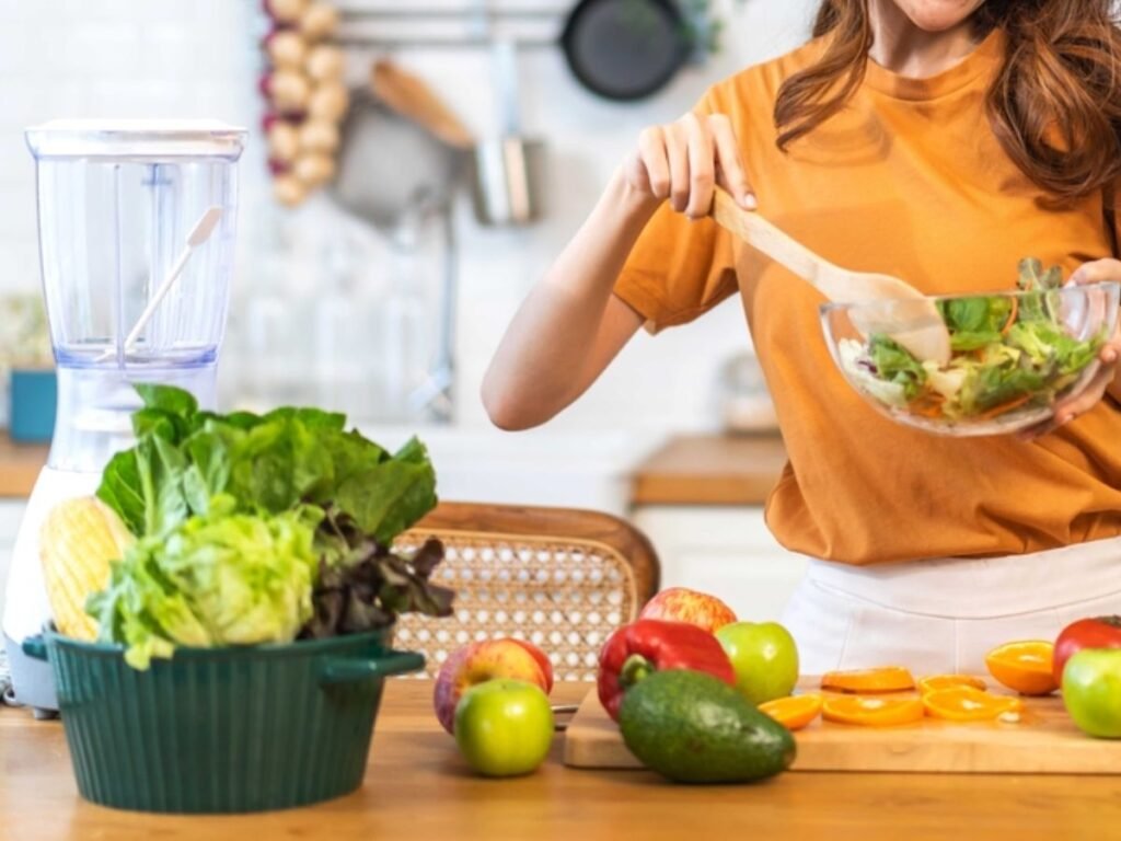 Woman preparing a fresh salad with lettuce, avocado, peppers and fruit for healthy weight loss meals