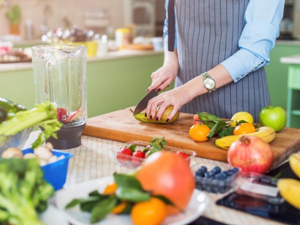 Woman slicing fresh fruit and vegetables on a cutting board to meal prep healthy meals