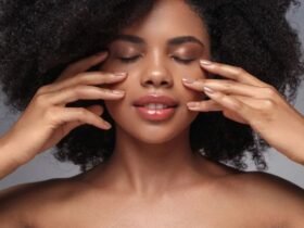 Woman with glowing skin gently touching her face with both hands, the kind of results people look for in Alloy skincare reviews