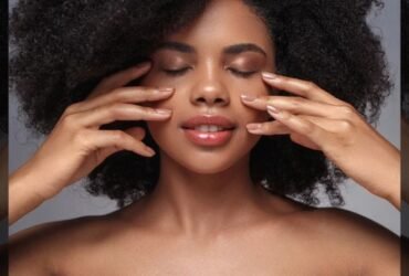 Woman with glowing skin gently touching her face with both hands, the kind of results people look for in Alloy skincare reviews