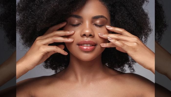 Woman with glowing skin gently touching her face with both hands, the kind of results people look for in Alloy skincare reviews
